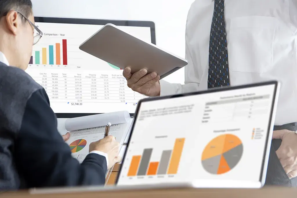 Reports with bar and pie charts on a laptop and a printed sheet