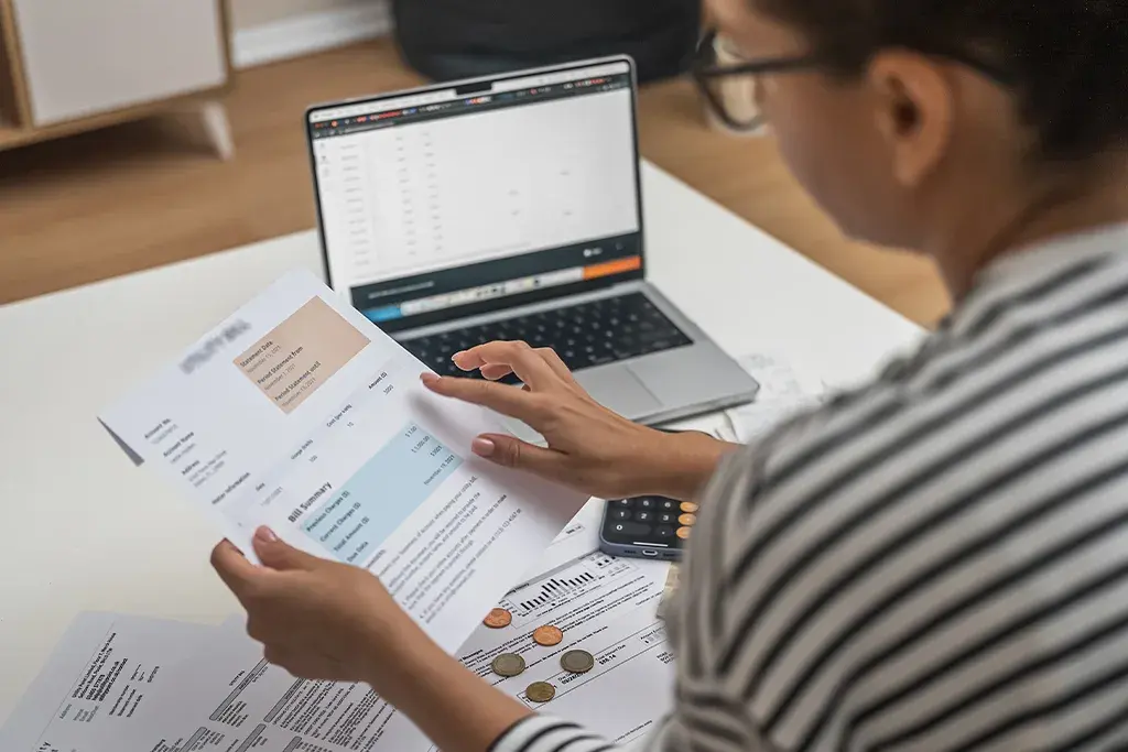 Statements and receipts being checked against the books on a laptop
