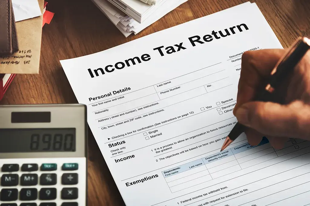 An income tax return form being filled in beside a calculator